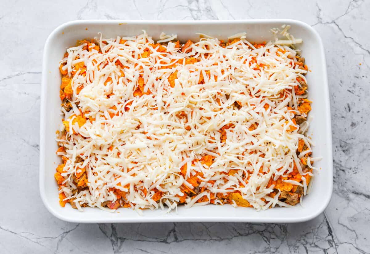 Doritos casserole is everything you love about taco night, just with a crunchy, cheesy twist! It’s crispy, crunchy, creamy, flavorful, and so easy to throw together. Who can say no to chips for dinner? Chips and cheese on top of the meat mixture in the baking dish.