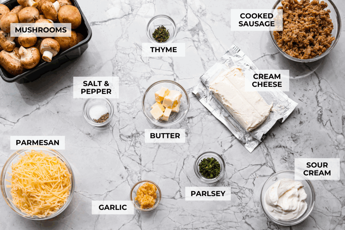 Trust me, this Stuffed Mushroom Dip is way easier (and honestly better) than making stuffed mushrooms. You skip all the filling and baking but still get that creamy, cheesy, herby, sausage flavor everyone’s obsessed with. Overhead shot of labeled stuffed mushroom dip ingredients.