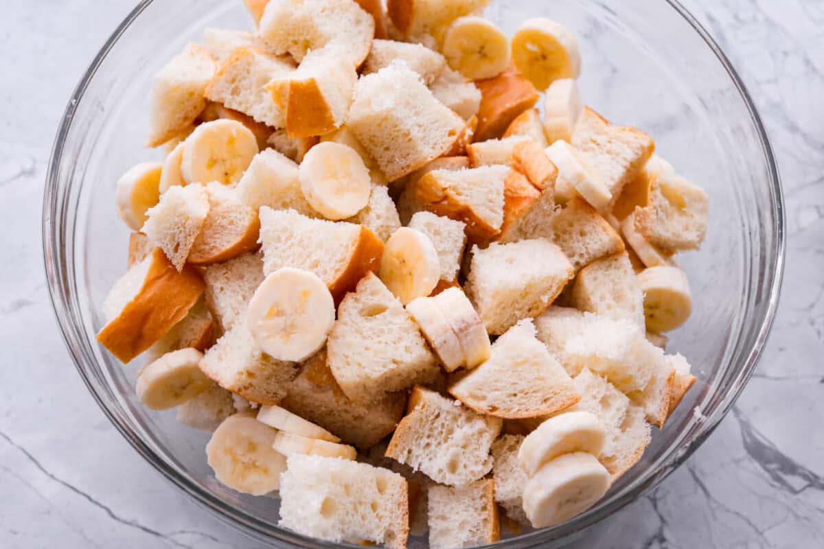 If you love classic bread pudding, you’ve got to try banana bread pudding. Sweet banana flavor, a soft custardy center, and golden edges that taste like heaven. It’s easy to throw together and is perfect for brunch or even dessert! Sliced banana added to the bowl of bread.