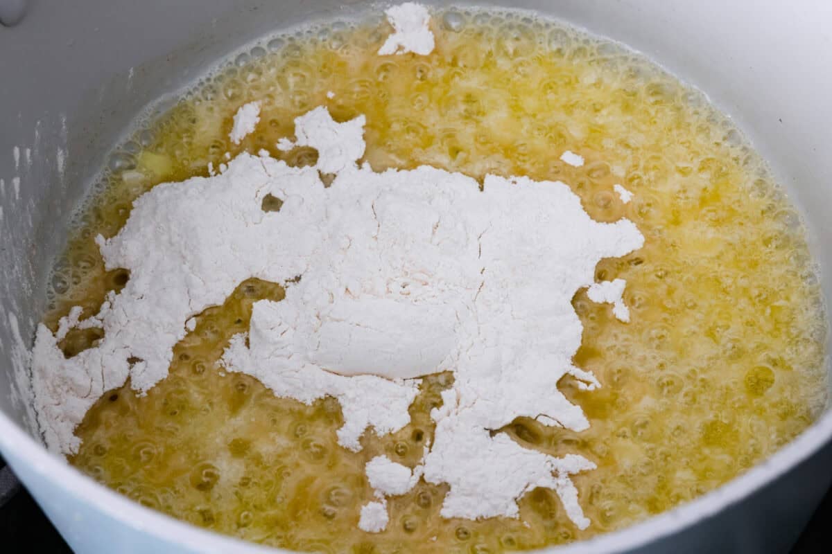 I promise that with just one bite of this copycat Panera Bread Broccoli Cheddar Soup, you'll be hooked! It's ultra creamy with broccoli, shredded carrots, and a hint of nutmeg, all cooked together with melted cheese. This soup is delicious and easy to make! Onions, melted butter and flour in pot.