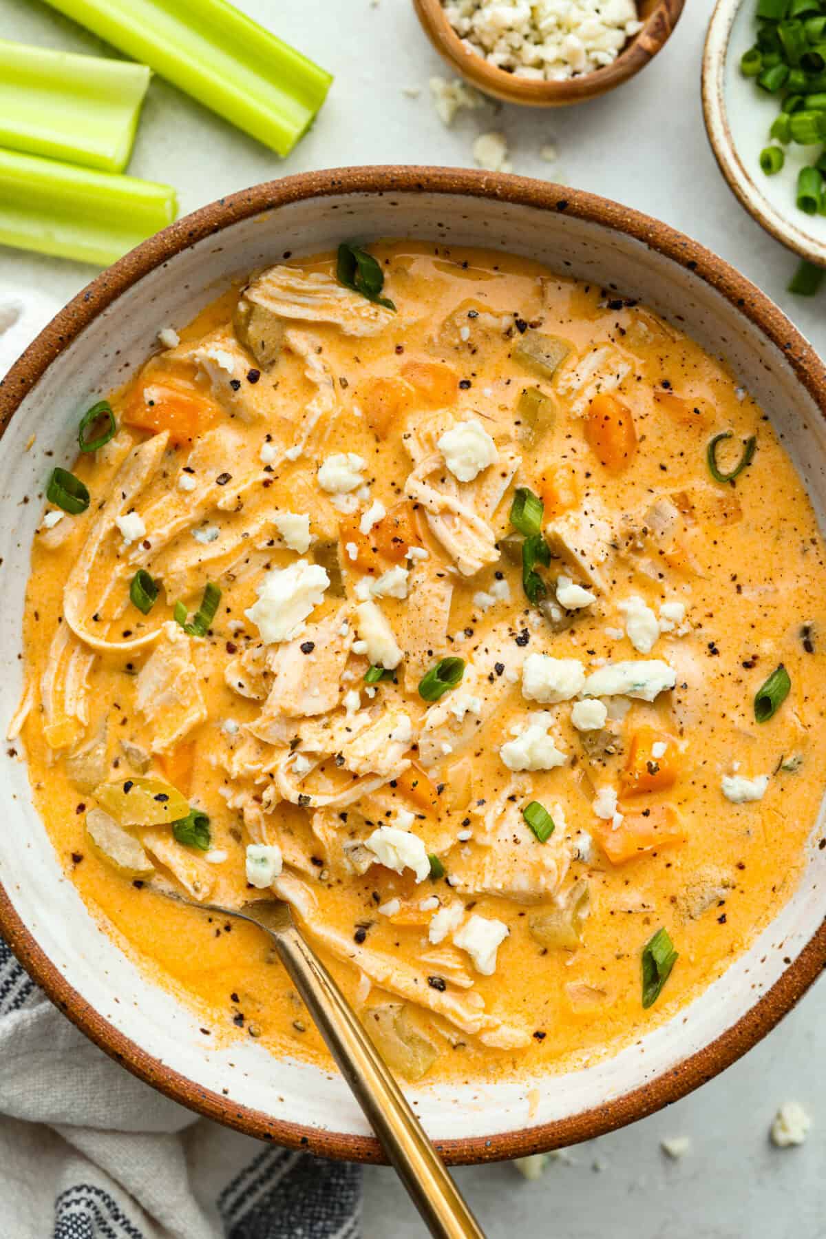 This buffalo chicken soup is about to be your new favorite! It’s creamy, spicy, and loaded with tender chicken and bold flavor, all ready in just 30 minutes. Perfect for busy weeknights, game day, or when you need a cozy meal with a little kick. Overhead shot of a bowl of buffalo chicken soup garnished with blue cheese crumbles and green onions.