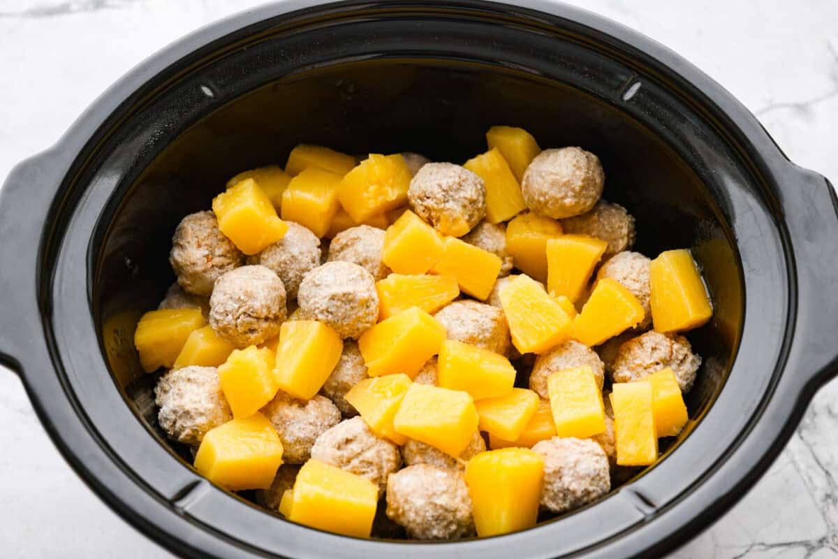 Pineapple chunks and meatballs in a crockpot.