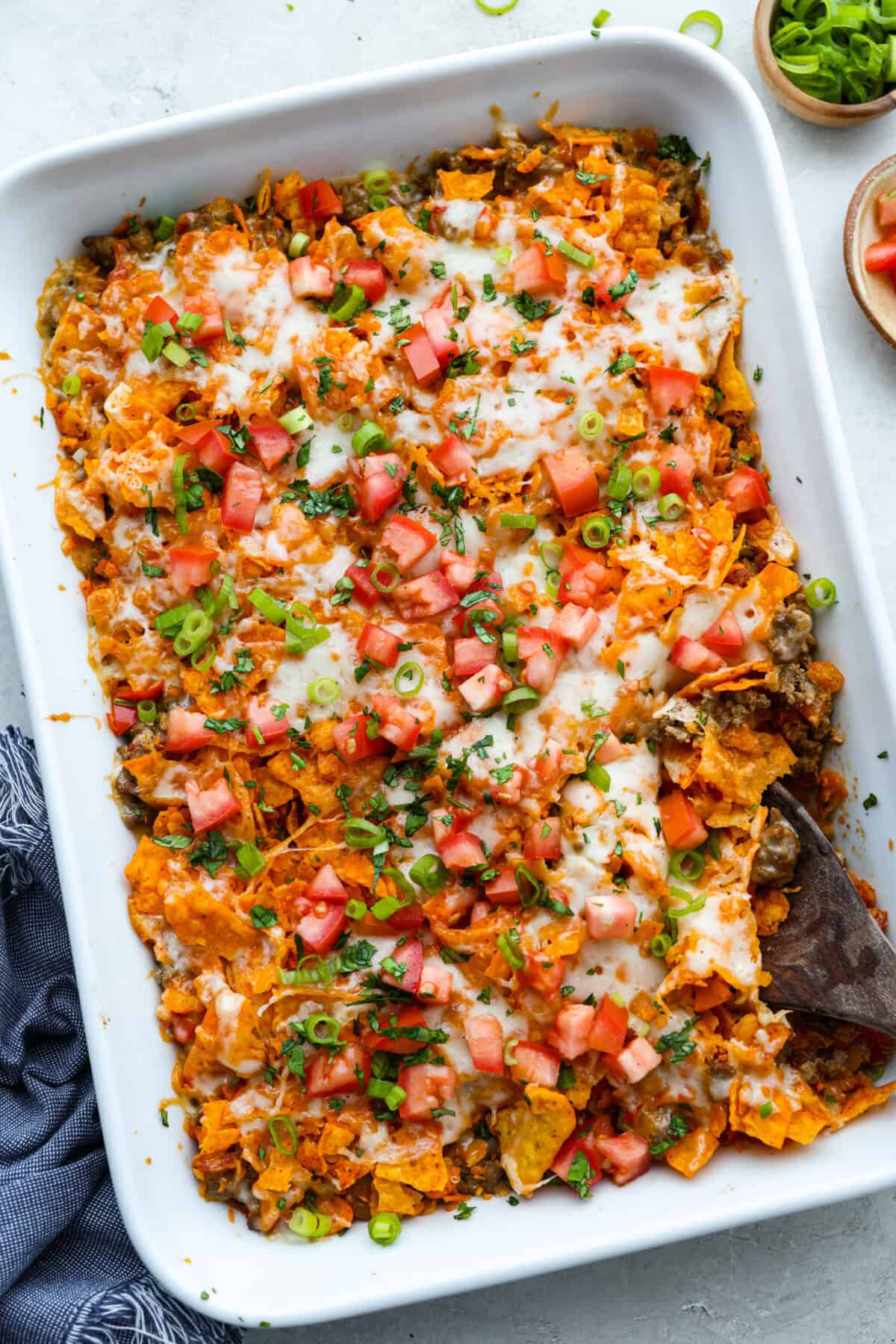 Doritos casserole is everything you love about taco night, just with a crunchy, cheesy twist! It’s crispy, crunchy, creamy, flavorful, and so easy to throw together. Who can say no to chips for dinner? Doritos casserole baked and topped with green onion, tomatoes and chopped cilantro.