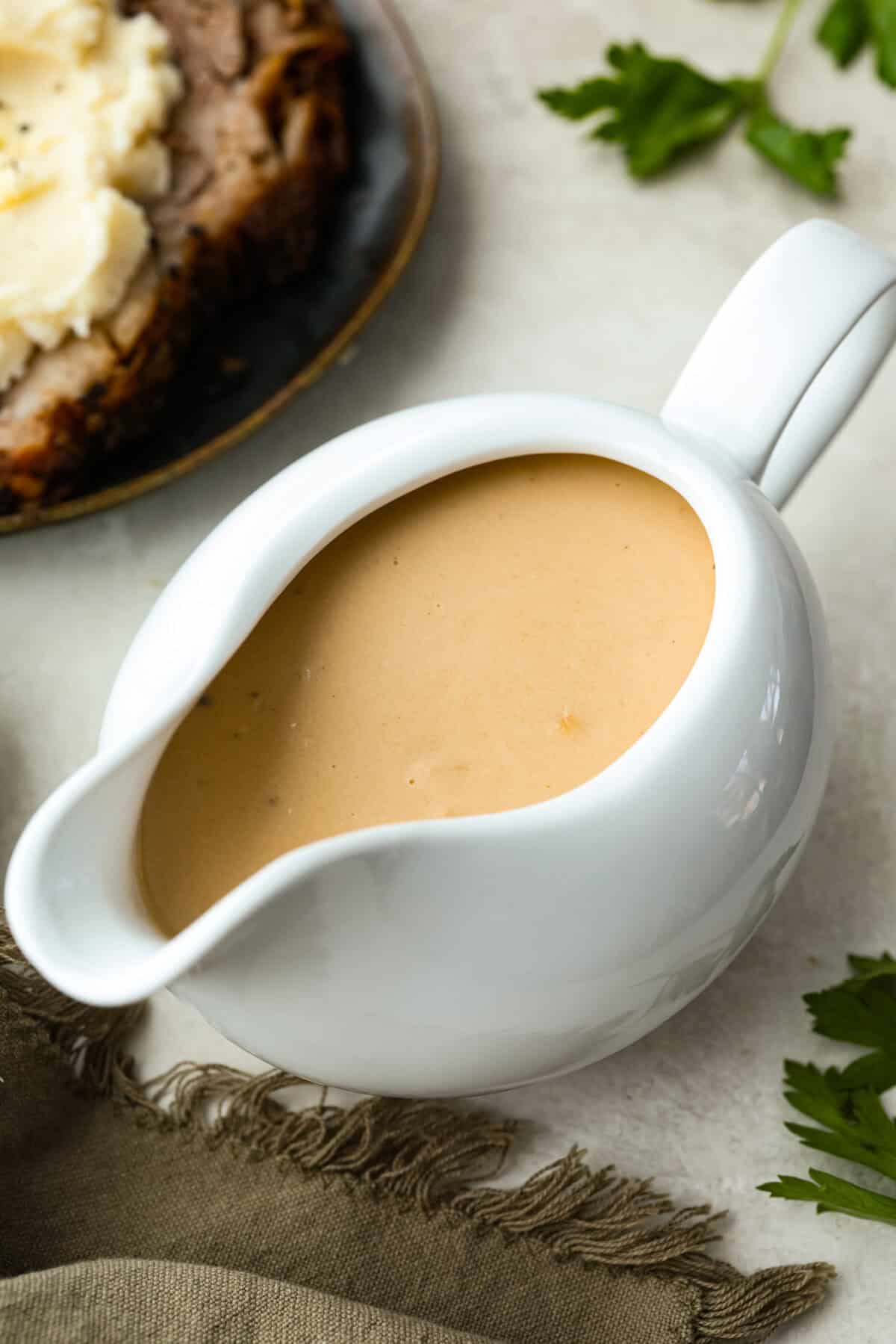 Turn those flavorful pan drippings into the creamiest gravy with a hint of tang. This sour cream gravy is rich, smooth, and so versatile. They are perfect over mashed potatoes, pork chops, but especially on my favorite Swedish Meatballs. Gravy boat filled with sour cream gravy.