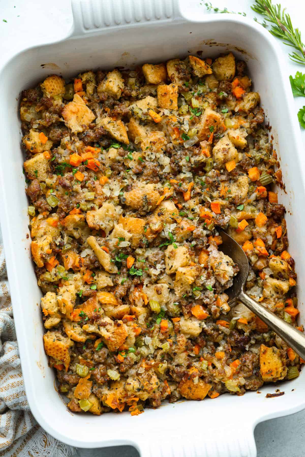 Why did it take me this long to use it in stuffing? Sourdough Stuffing's tangy crust and the chewy middle are perfection! Every bite soaks up all that buttery, herby goodness like it was made for this. Baking dish with sourdough stuffing and a serving spoon.