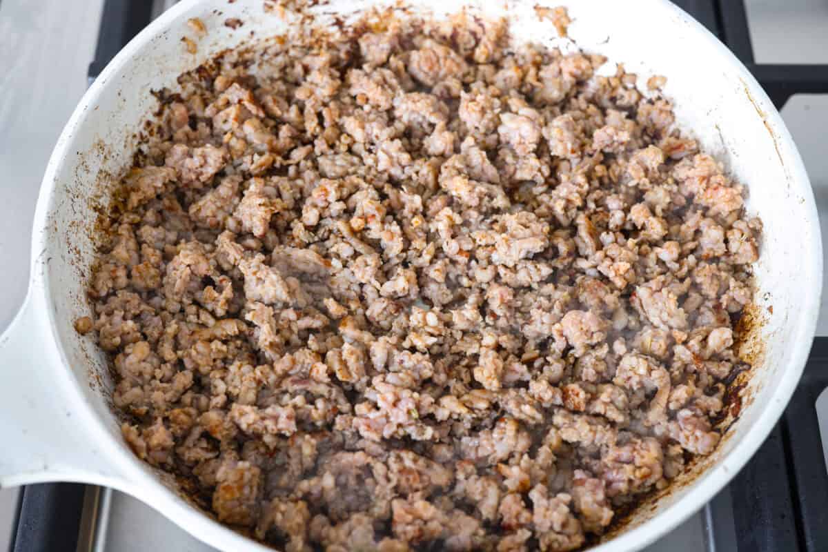 Why did it take me this long to use it in stuffing? Sourdough Stuffing's tangy crust and the chewy middle are perfection! Every bite soaks up all that buttery, herby goodness like it was made for this. Sausage cooking in a skillet.