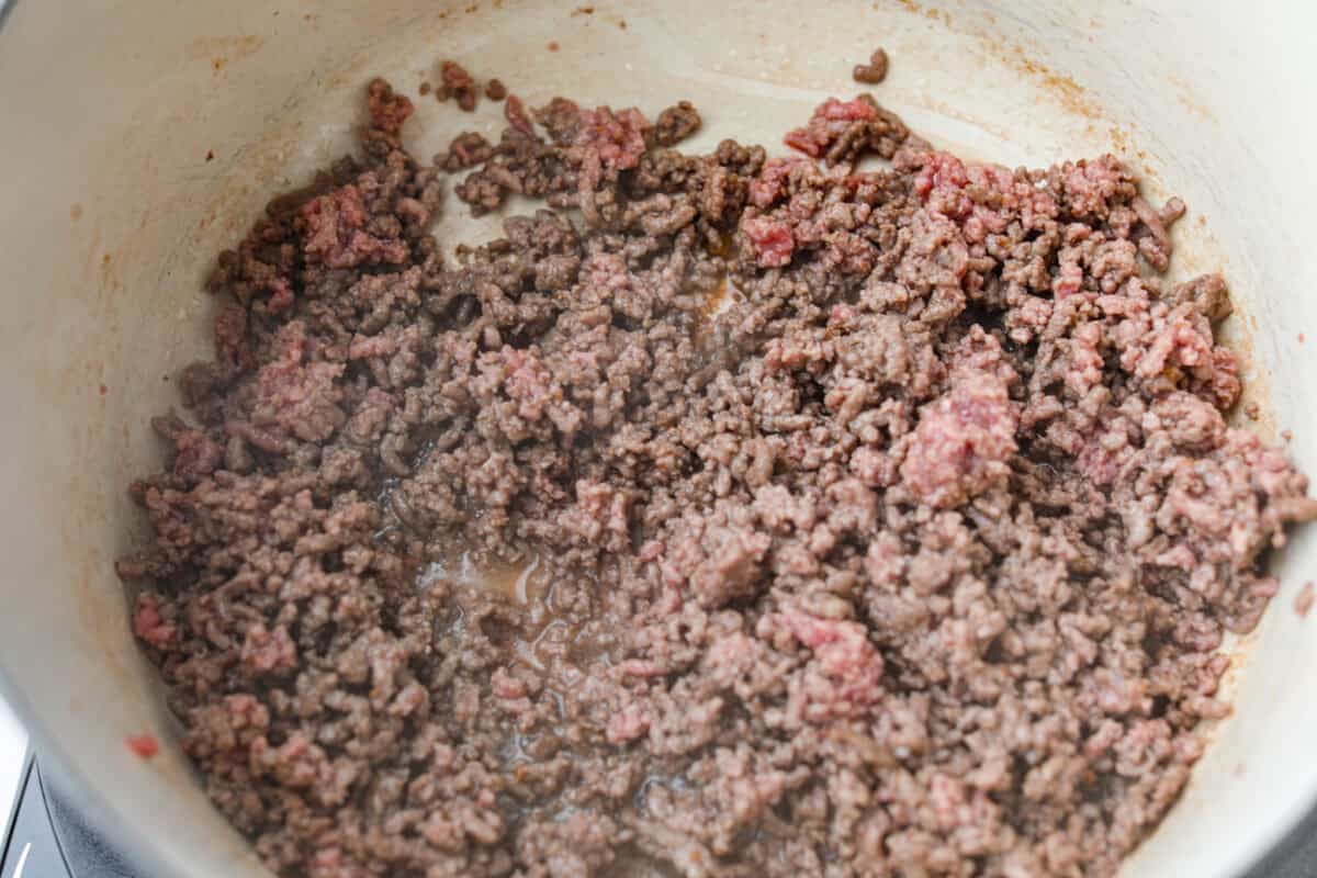 My Texas Cowboy Stew actually fills up my always-hungry boys! That's because it's loaded with smoky bacon, spicy sausage, ground beef, and potatoes. They all simmer together in a rich broth for a hearty stew. Ground beef cooking in some of the bacon grease.