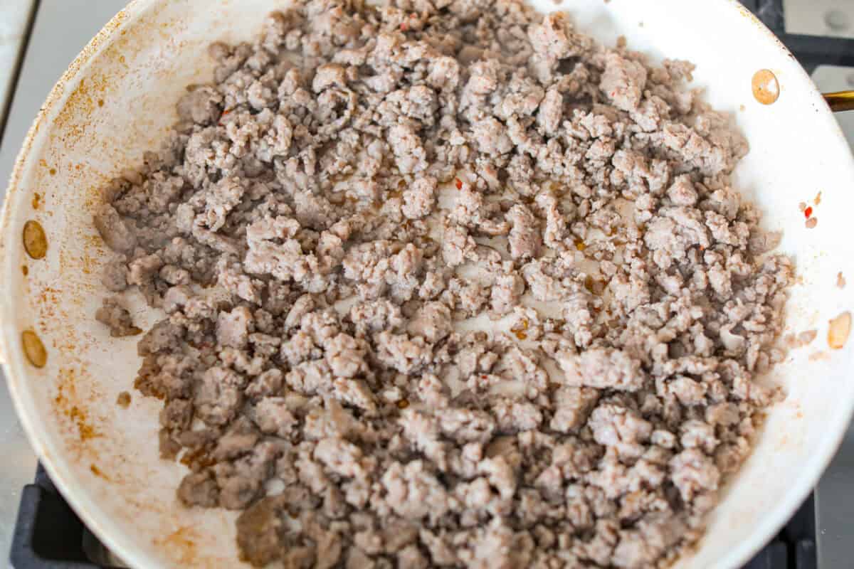 Wake up to a breakfast that feels like a warm hug! This Christmas morning casserole turns sausage, eggs, cheese, and fluffy biscuits into the easiest, hearty breakfast you can't get enough of! Sausage cooking in a skillet.