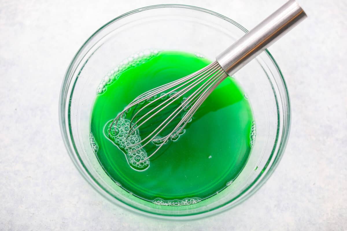 Lime Jello whisked with boiling water in a larg mixing bowl. 