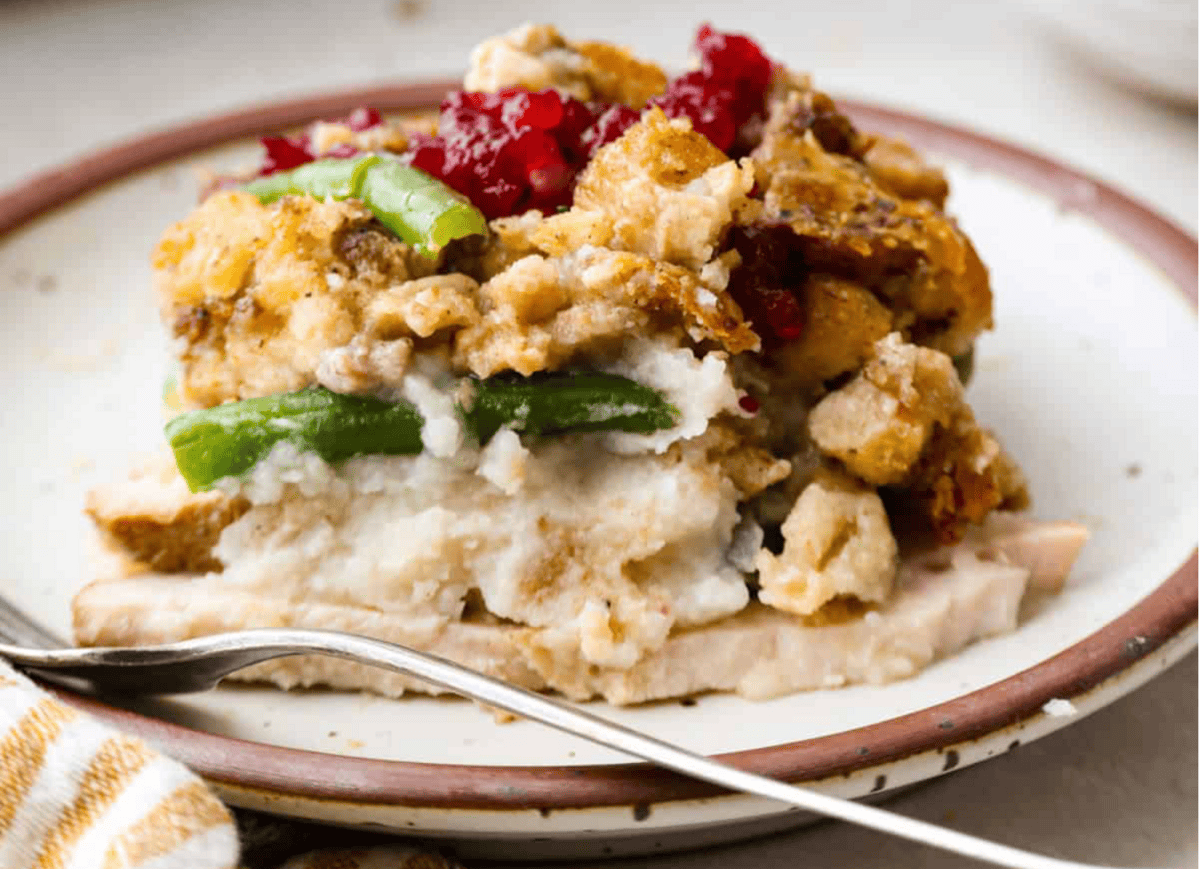 I love Thanksgiving leftovers because when I use them, it saves me time, it saves me money. A photo of Thanksgiving Casserole on a plate with a silver fork.