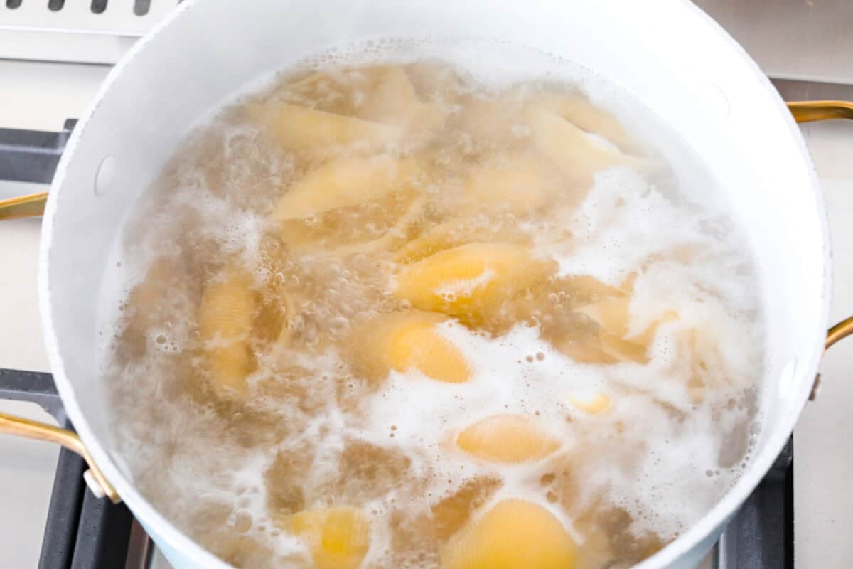 Million dollar stuffed shells take all the creamy, cheesy goodness of the classic and wrap it into fun jumbo shells. It’s cozy, everyone loves it, and it's easy to make! Jumbo pasta shells boiling in a large pot.