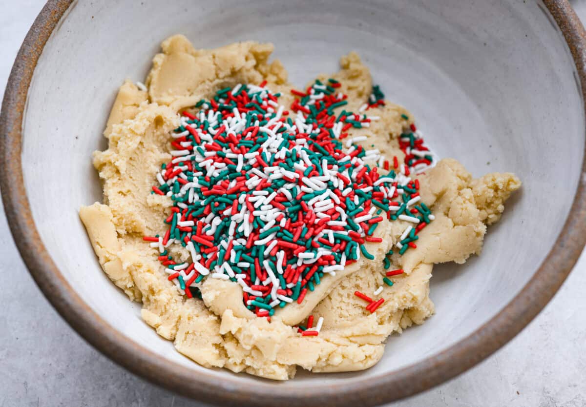 These sprinkle cookies are pure joy. Soft centers, chewy edges, and lots of colorful sprinkles! They are perfect for Christmas parties, cookie exchanges, and neighbor gifts. Cookie dough with sprinkles added to it.