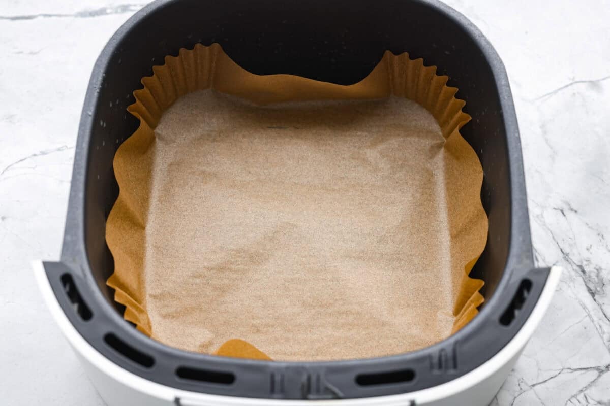 If you don’t normally love Brussels sprouts, this version might surprise you. The air fryer makes these brown sugar Brussels sprouts crisp, done in minutes, and the brown sugar caramelizes them perfectly! Air fryer basket with and air fryer parchment liner in it.