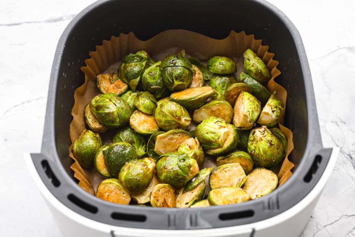 If you don’t normally love Brussels sprouts, this version might surprise you. The air fryer makes these brown sugar Brussels sprouts crisp, done in minutes, and the brown sugar caramelizes them perfectly! Sauce coated sprouts in the air fryer basket ready to be cooked.