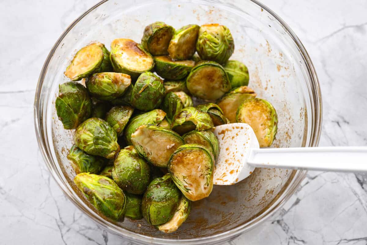 If you don’t normally love Brussels sprouts, this version might surprise you. The air fryer makes these brown sugar Brussels sprouts crisp, done in minutes, and the brown sugar caramelizes them perfectly! Someone stirring the Brussels sprouts with the brown sugar sauce.
