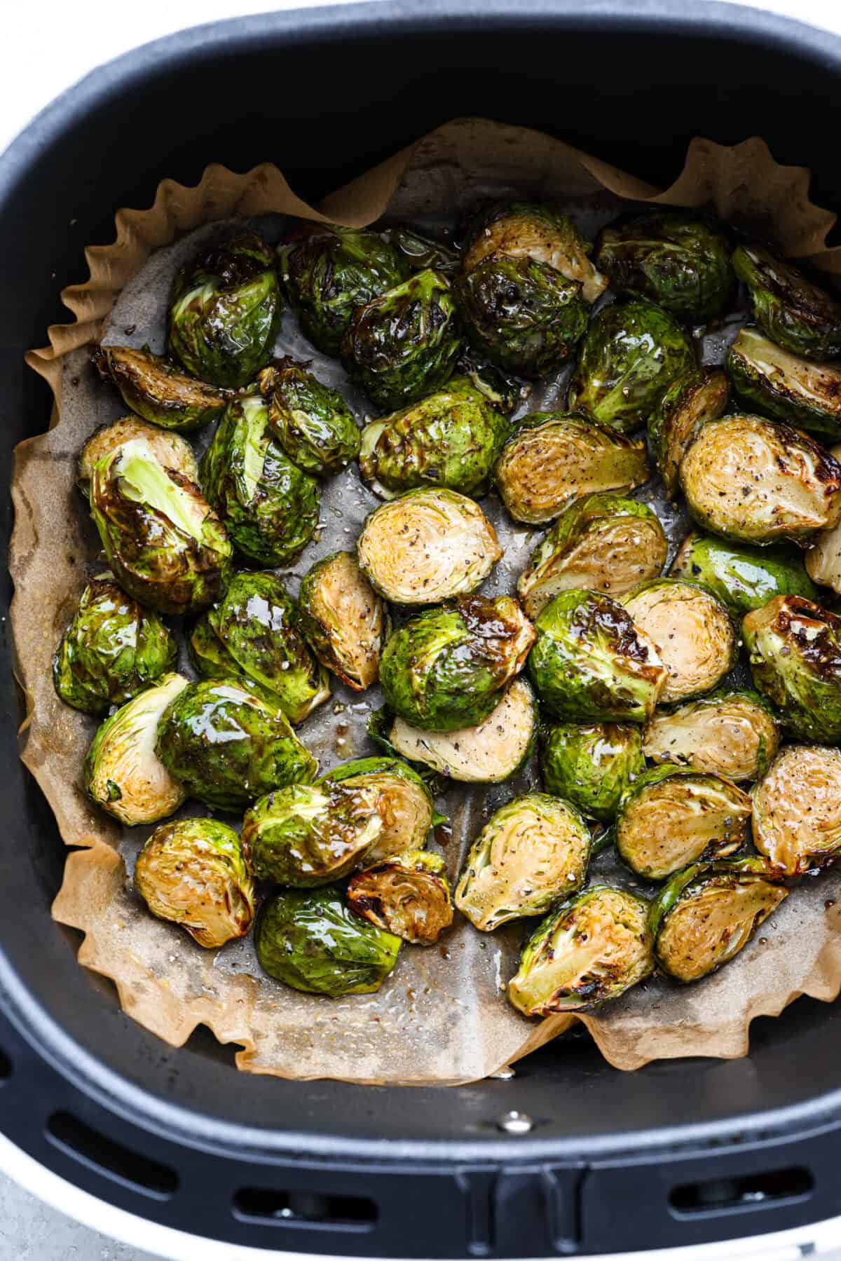 If you don’t normally love Brussels sprouts, this version might surprise you. The air fryer makes these brown sugar Brussels sprouts crisp, done in minutes, and the brown sugar caramelizes them perfectly! Cooked air fryer Brussels sprouts still in the air fryer basket.