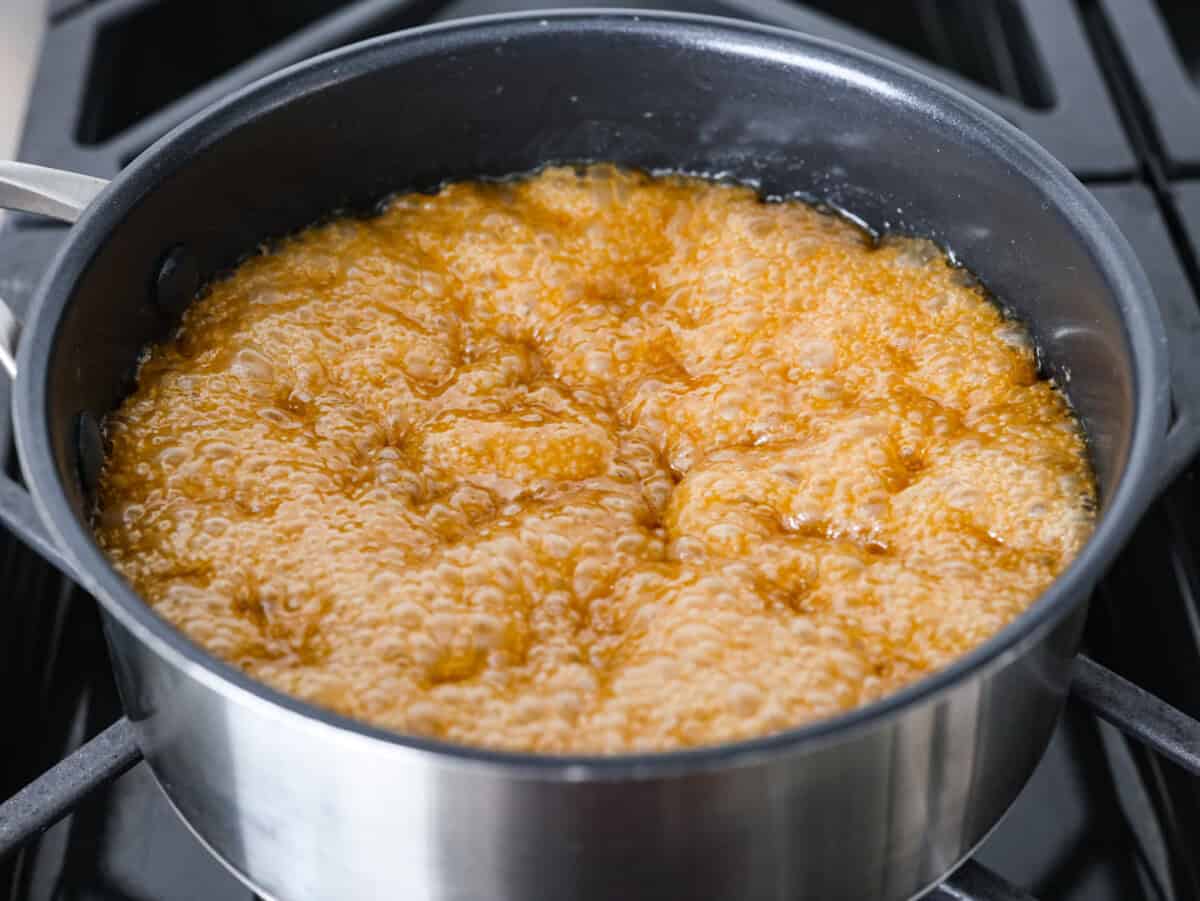 If you want a quick, crunchy treat with a bit of holiday mischief, this Grinch Christmas Crack is it. Sweet, salty, and totally addictive. My classic Christmas Crack is always a hit, but this version brings all the Grinchy fun! Toffee ingredients boiling in a pot on a stove.