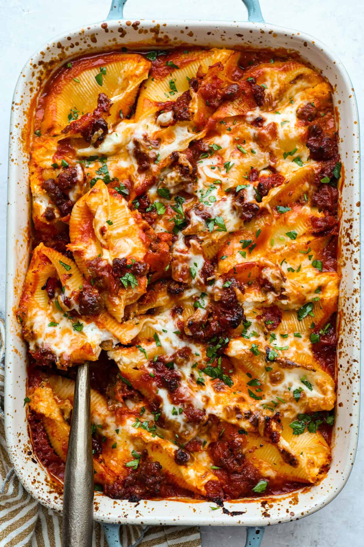 Million dollar stuffed shells take all the creamy, cheesy goodness of the classic and wrap it into fun jumbo shells. It’s cozy, everyone loves it, and it's easy to make! Overhead shot of the baked million dollar stuffed shells in a baking dish.