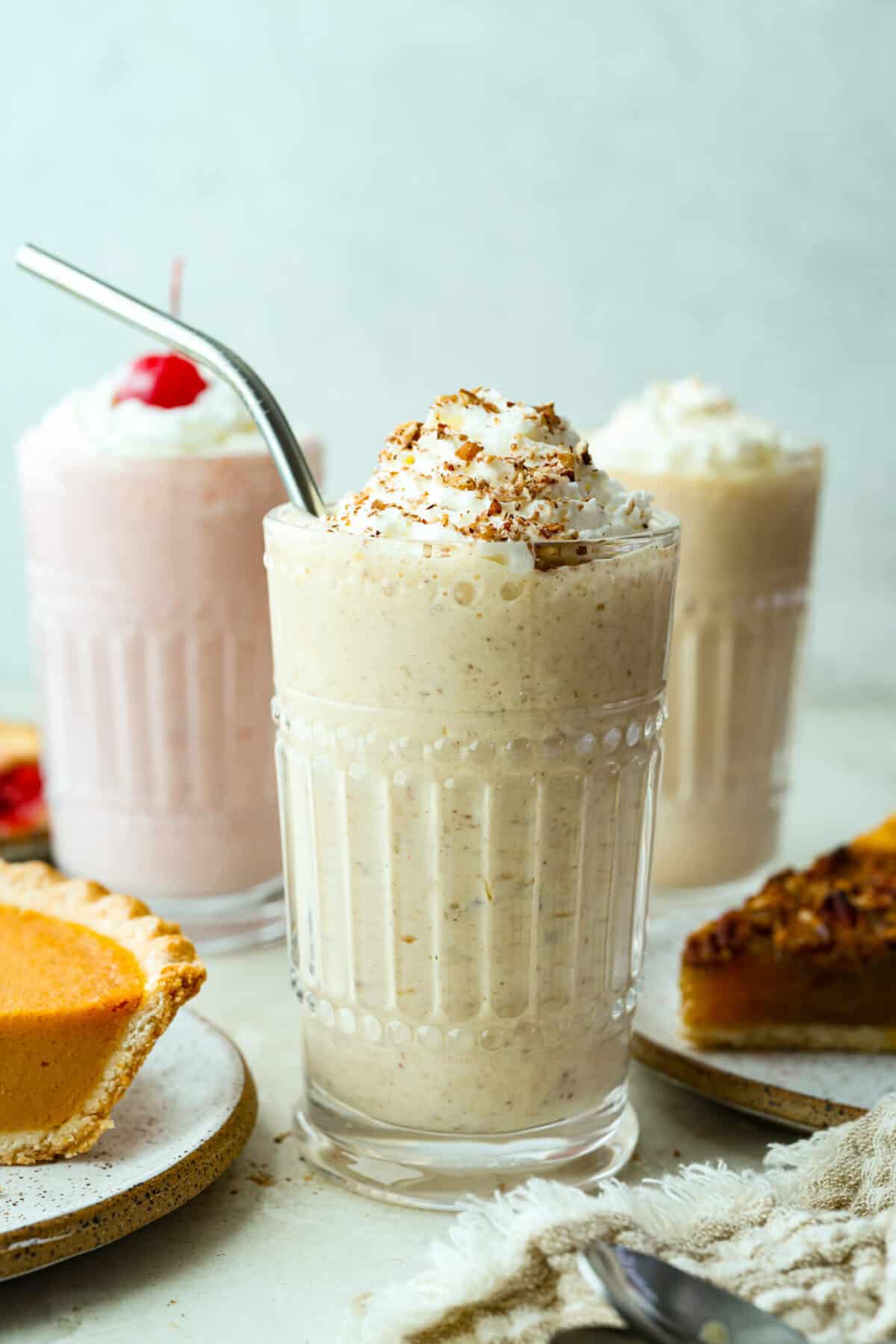 Leftover pie milkshakes are the sweetest way to give your extra pie new life! Just grab a slice, blend it with creamy ice cream, and sip your way to dessert bliss. 3 different pie milkshakes in cte decorative glasses next to slices of pie.