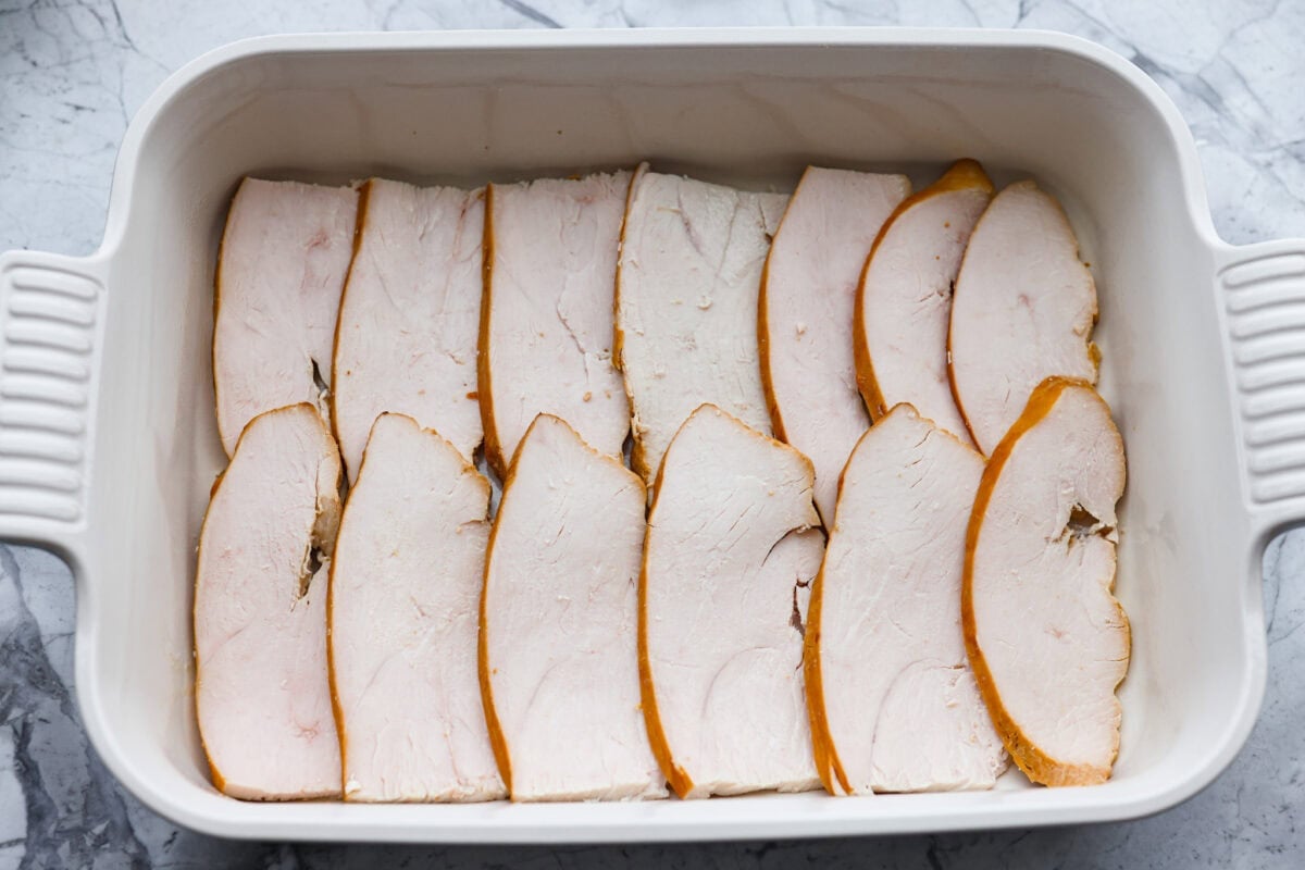 Turkey slices layered on the bottom of a baking dish. 