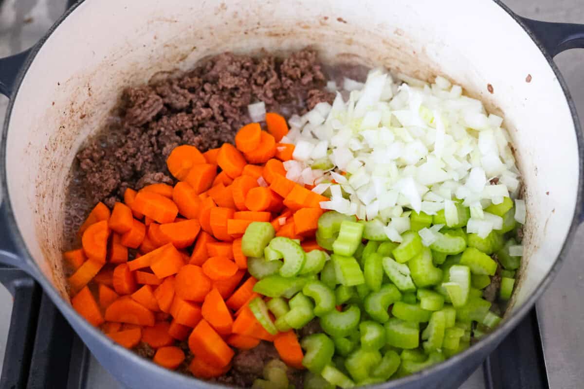 Pot with cooked ground beef and onion, carrot, and celery.
