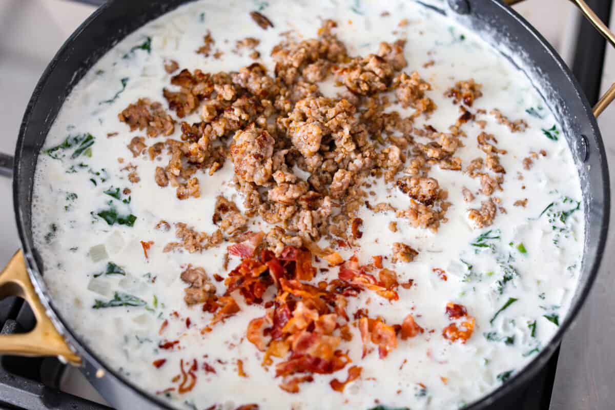 I am begging you guys to make this Zuppa Toscana Casserole! It turns the classic soup into the most delicious bake! It has layers of potatoes, sausage, bacon, kale, and cheese drenched in the most amazing sauce! Make it today, trust me! Cream, broth, cheese seasonings and meats added to the skillet.