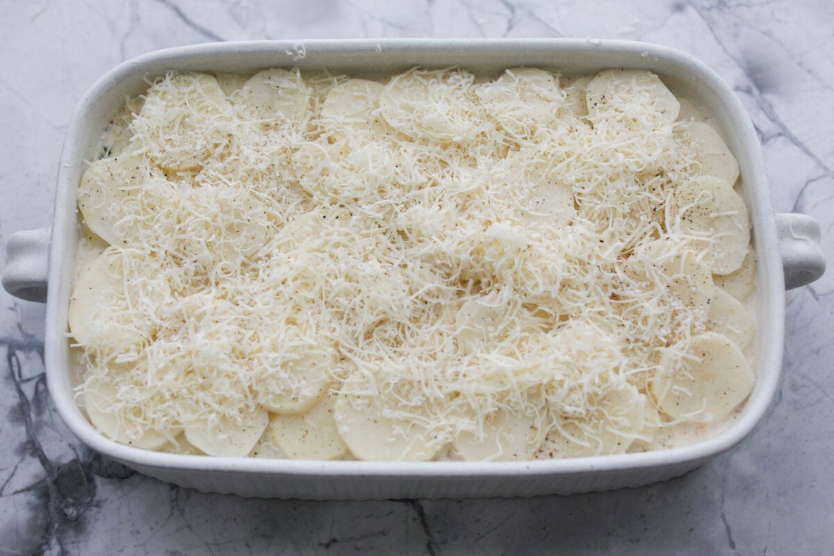 I am begging you guys to make this Zuppa Toscana Casserole! It turns the classic soup into the most delicious bake! It has layers of potatoes, sausage, bacon, kale, and cheese drenched in the most amazing sauce! Make it today, trust me! A layer of potatoes and cheese added to the top of the sauce mixture.