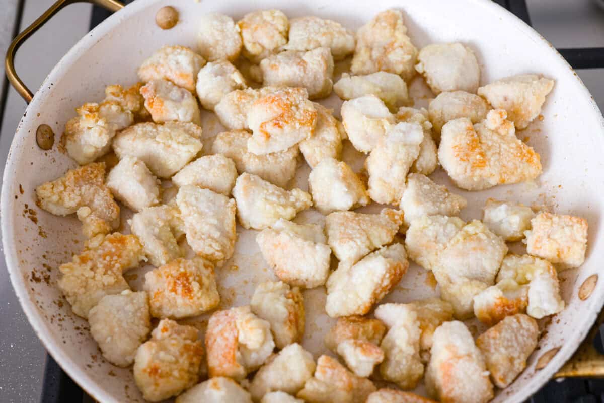 You love my baked General Tso’s chicken, so obviously, I had to make a faster one. This one pan General Tso's chicken is sticky, saucy, and on the table in about 30 minutes. Cornstarch covered chicken cooking in a skillet on the stove.