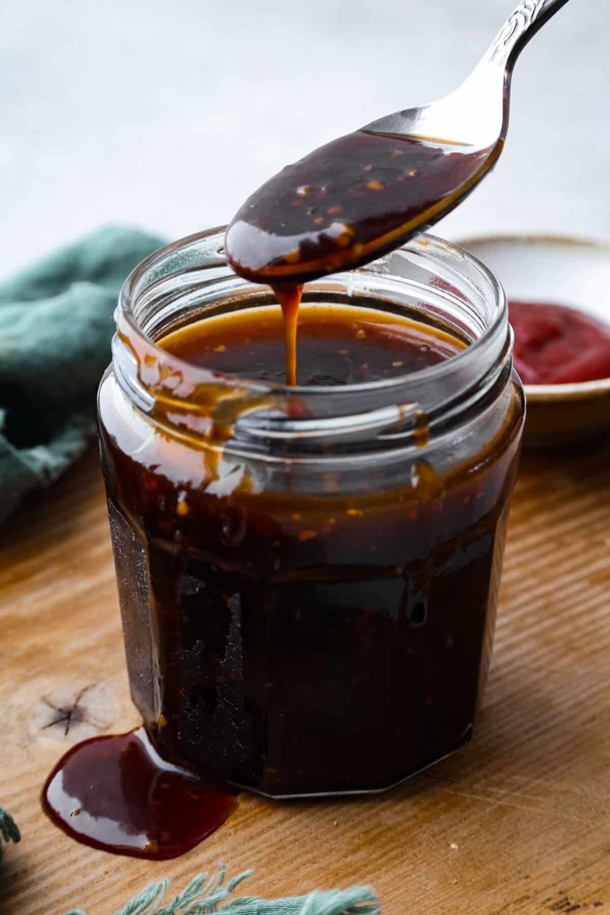 Korean BBQ sauce is the kind of pantry staple that turns random weeknight ingredients into something irresistible. Use it to glaze salmon, coat wings, toss with chicken and veggies, or turn into a killer Korean BBQ pizza Someone dripping a spoonful of Korean bbq sauce from a jar.