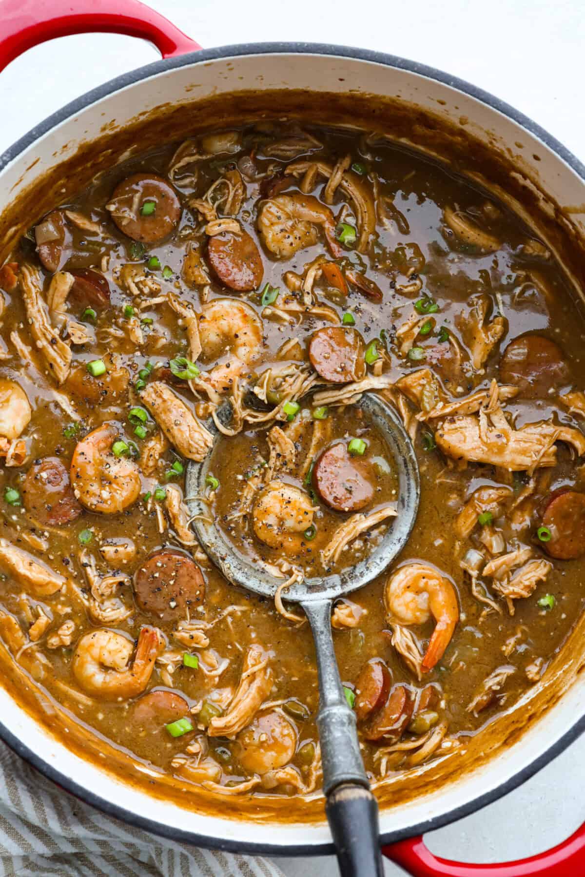 After listening to your feedback and learning what makes a great New Orleans gumbo, I made some changes. This version is richer, more balanced, and way closer to the real deal, without being overwhelming to make at home. Large pot of New Orleans gumbo with a silver ladle.