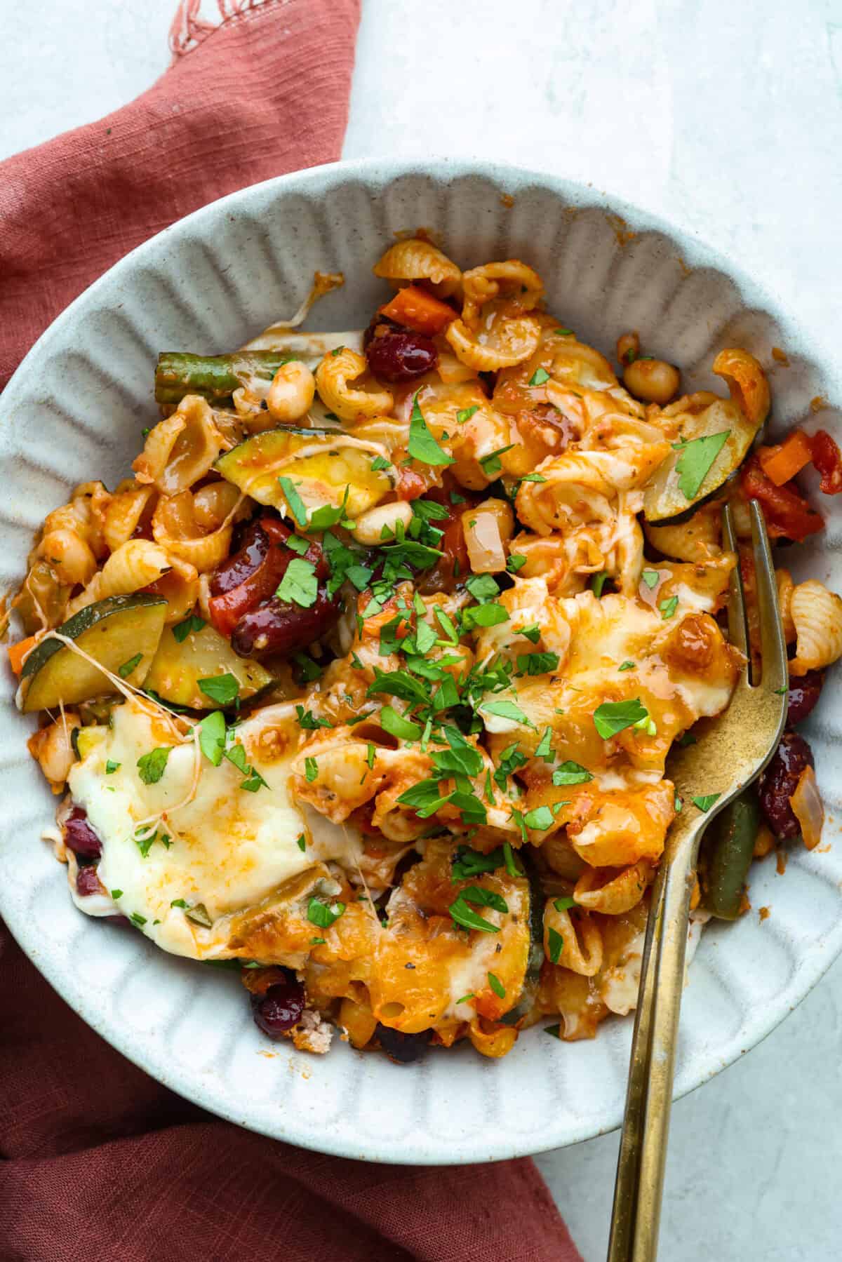 Serving portion of minestrone casserole with a gold fork. 