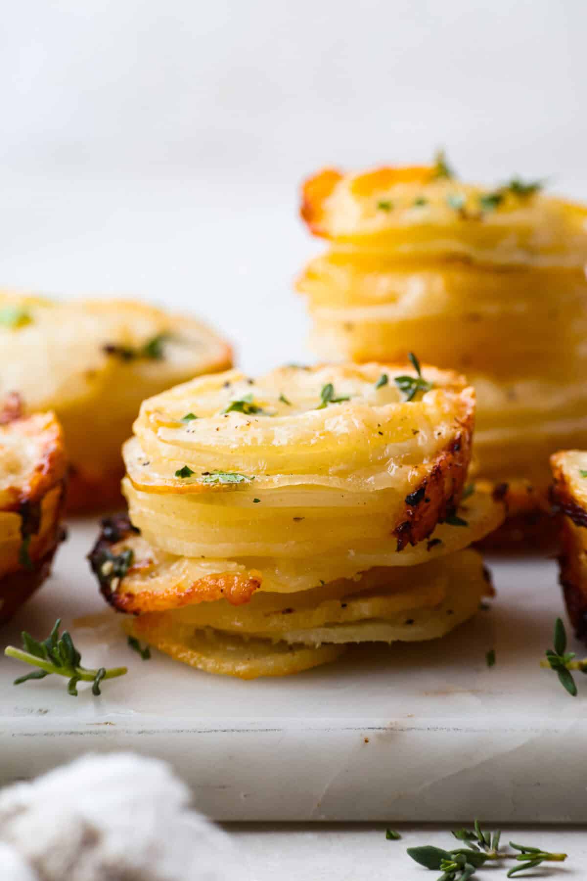 My crispy potato stacks take everything you love about cheesy, golden potatoes and turn it into an easy side dish. Thin slices bake into crisp edges and tender centers, with melty cheese and dripping with seasoned garlic butter! Side view of potato stacks.