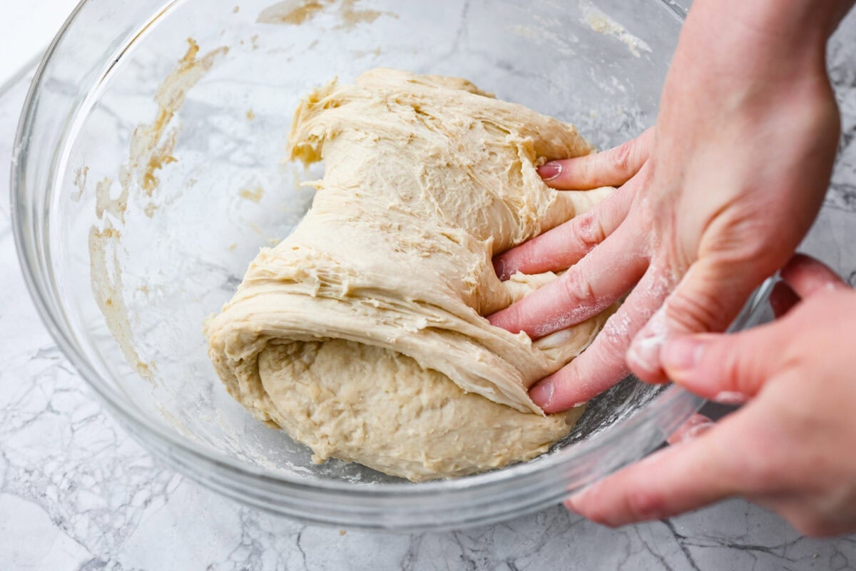Myย 4-ingredient artisan breadย is simple, rustic, and completely bakery-worthy. With just flour, water, yeast, and salt, youโll get a loaf with a crusty outside and a soft, chewy center. Someone pulling and smashing one side of the dough ball over the whole dough ball.