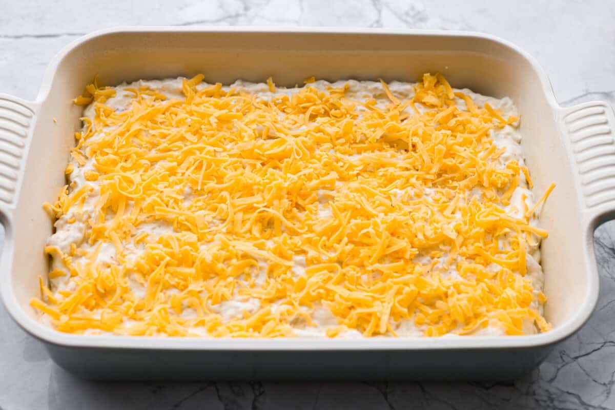 This crack orzo bake is creamy, cheesy, and packed with that irresistible ranch, bacon, and cheddar “crack” flavor everyone loves. It’s an easy casserole that’s guaranteed to be a hit. Chicken mixture covered in cheese ready to be baked.
