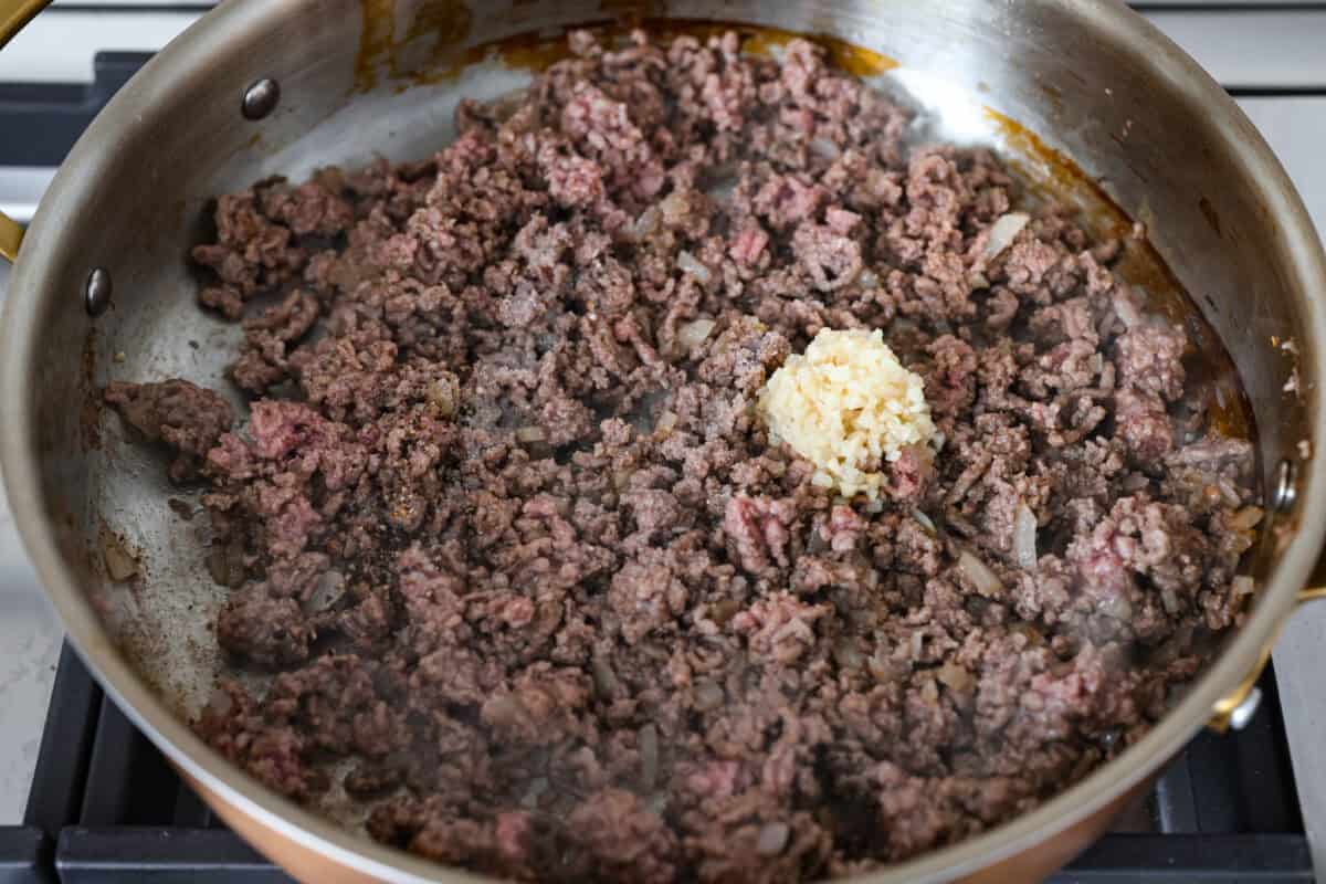 Ground beef and garlic cooking in a skillet. 