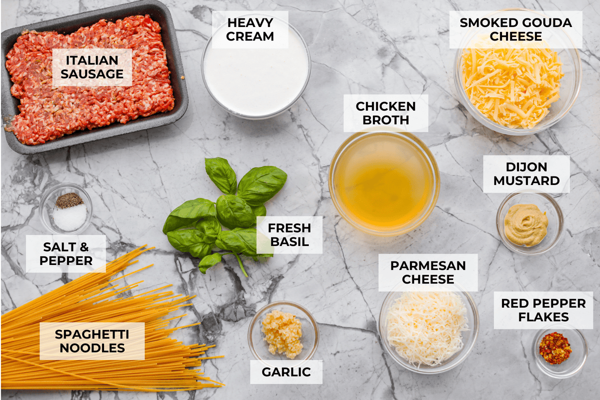 If you love a creamy pasta with big flavor, this creamy sausage spaghetti needs to be on your menu. Smoked Gouda adds depth, the sausage brings a little heat, and fresh basil adds brightness. Simple ingredients, quick to make, and always a hit! Overhead shot of labeled creamy sausage spaghetti ingredients.