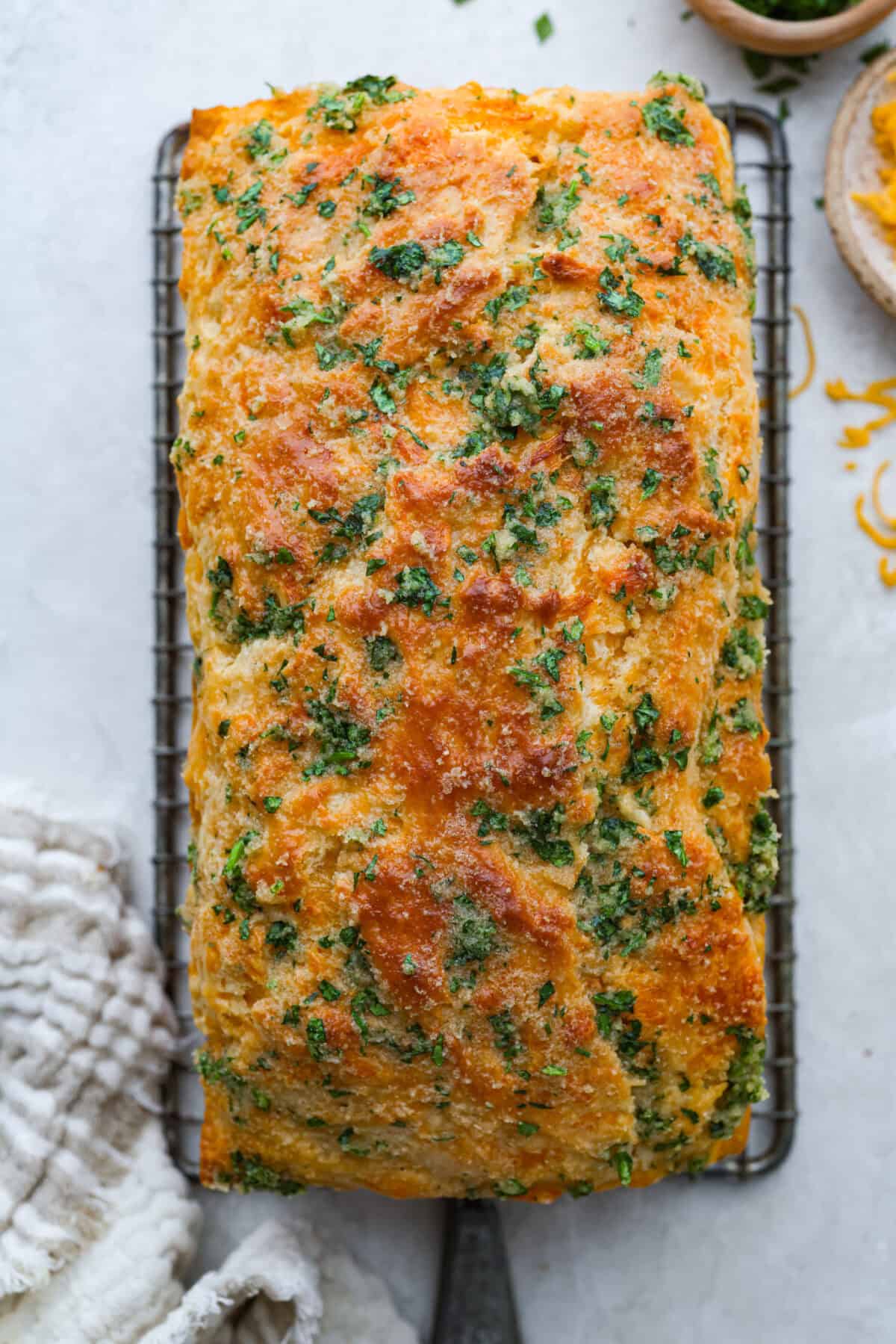Overhead shot of the cheddar bay biscuit bread loaf baked and cooking on a wire rack. 