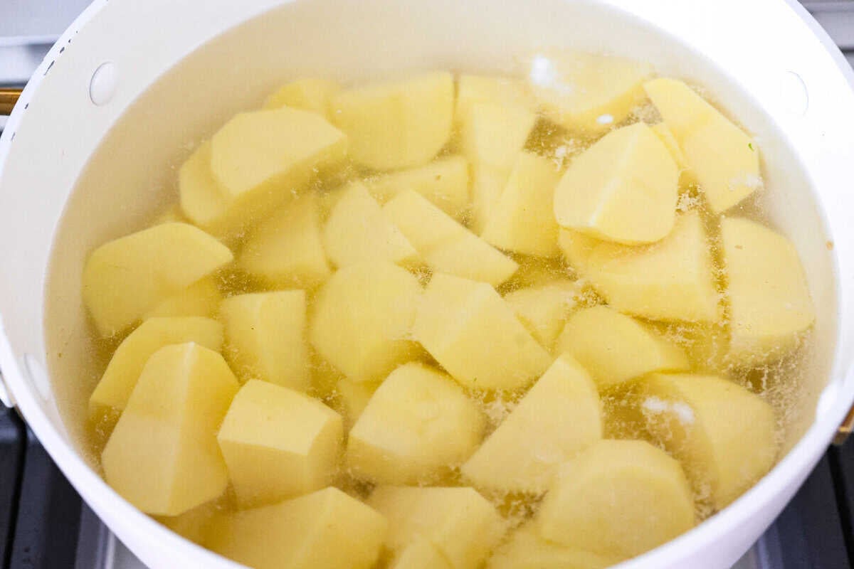 Irish Champion Potatoes are properly mashed potatoes. Tender potatoes combine with warm onions, added milk, and a generous dollop of Irish butter for a simple, rustic, and oh-so-good side dish! Potatoes peeled, cut and ready to cook in boiling water.