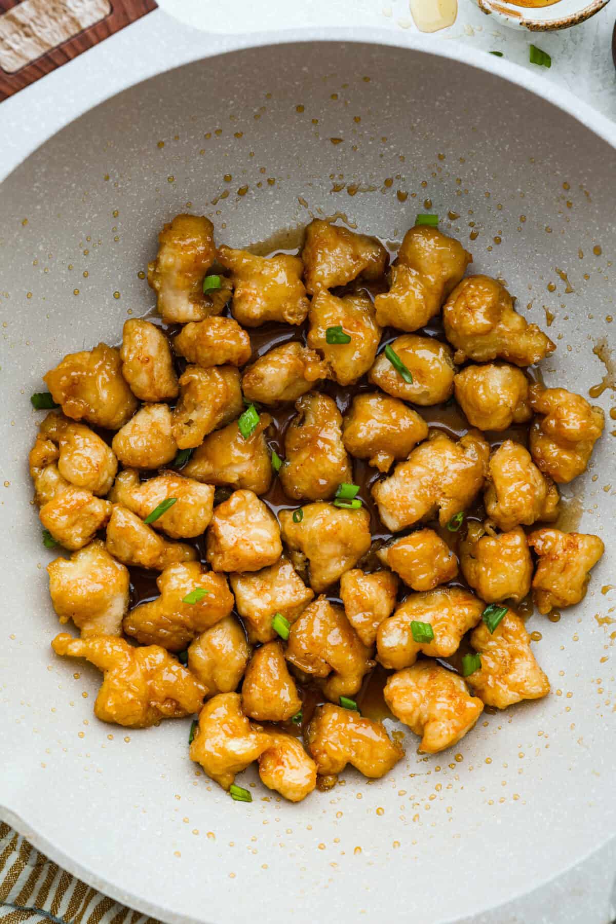 Skip takeout and make this PF Chang’s honey chicken in your own kitchen! Crispy fried chicken gets coated in a glossy honey sauce that’s sweet, savory, and hard to resist Top down shot of a wok with fried chicken pieces covered in the honey sauce and garnished with green onions.