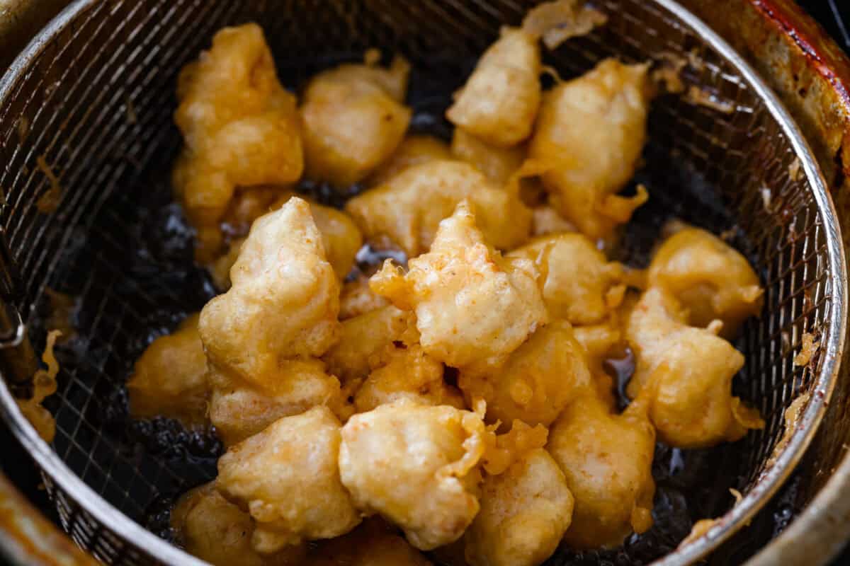 Skip takeout and make this PF Chang’s honey chicken in your own kitchen! Crispy fried chicken gets coated in a glossy honey sauce that’s sweet, savory, and hard to resist Chicken pieces frying in a deep fryer basket.