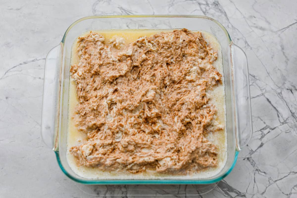 These cinnamon roll butter swim biscuits are my cheat code to making "cinnamon rolls." They bake up soft and fluffy with a sweet cinnamon swirl and icing on top. They disappear almost as fast as you can make them! Melted butter added to the baking dish and biscuit mixture on top.