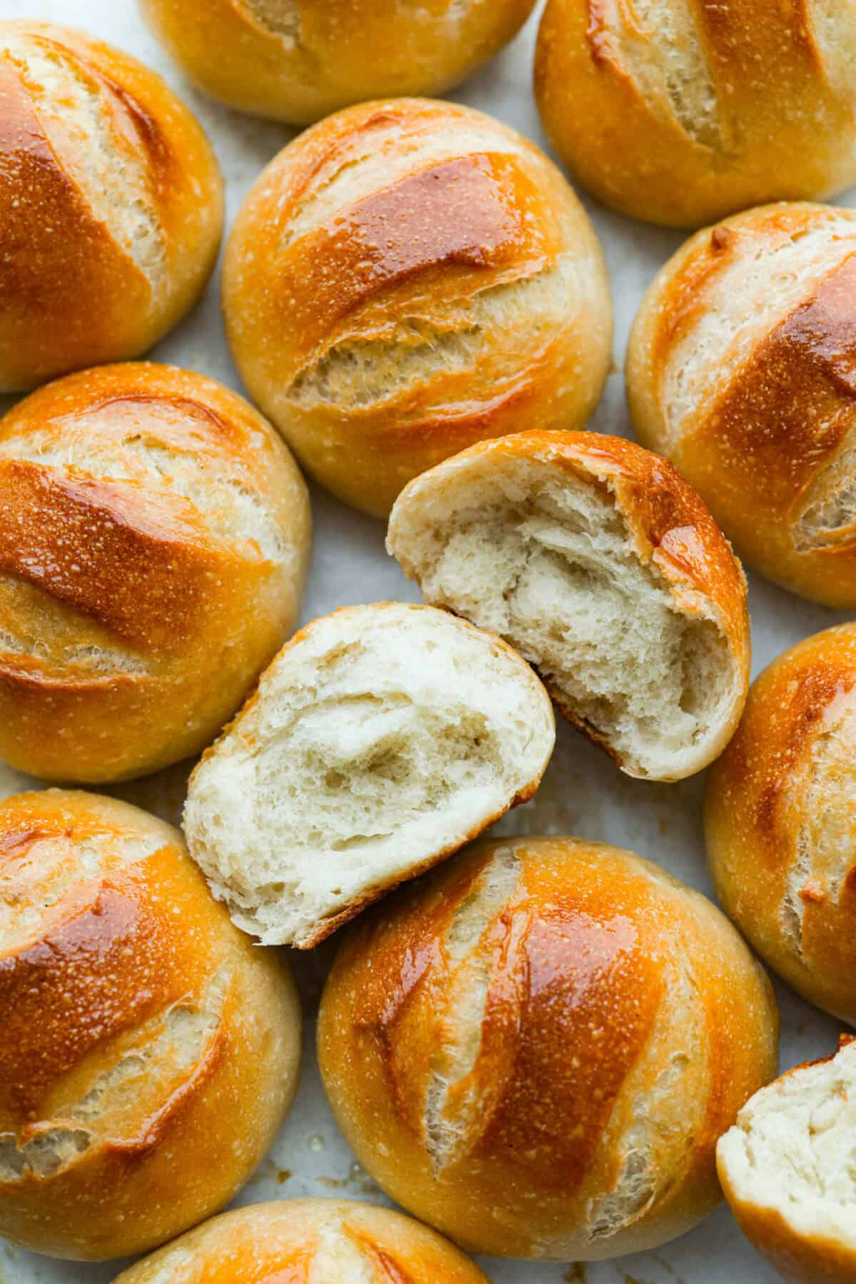 If warm, homemade bread is your weakness, you’re going to love these French bread rolls. They’re soft, chewy, and perfect for everything from weeknight dinners to holiday meals. French bread rolls all on a surface with one split in half so we can see the soft center and crunchy outside.