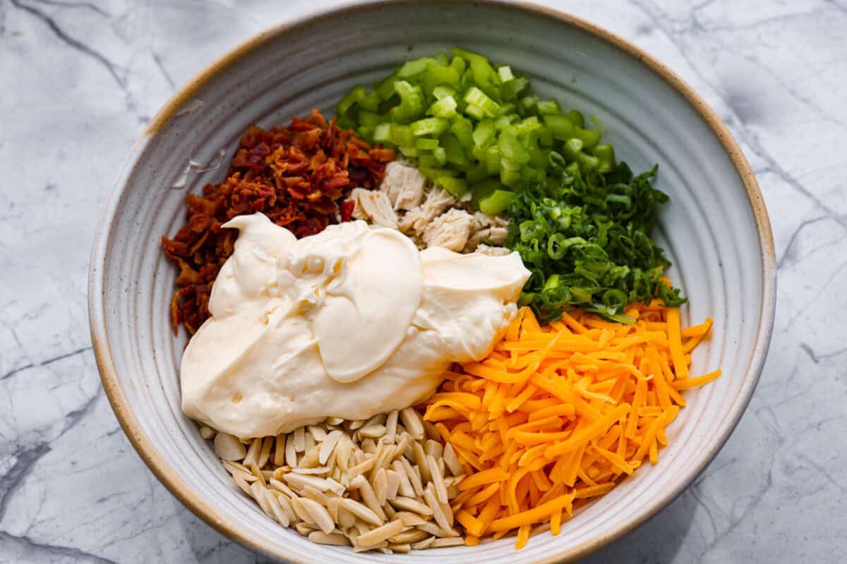 Million dollar chicken salad totally lives up to the name. It’s creamy, cheesy, crunchy, and packed with bacon, so every bite is full of flavor. Serve it on croissants, with crackers, or straight from the bowl! It's that good. Mayonnaise added to the bowl of ingredients.