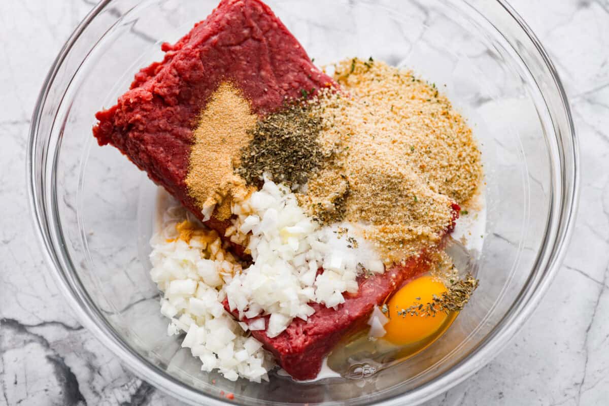 Meatloaf is even better in mini form! These mini meatloaf muffins are tender, flavorful, and topped with a sweet, tangy glaze. They are done in about 25 minutes, making them perfect for an easy dinner I know the kids will love. All of the meatloaf ingredients added to a bowl.