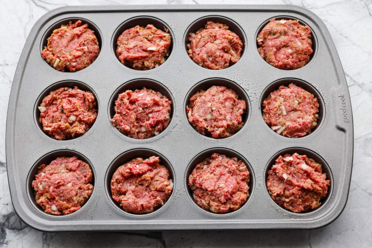 Meatloaf is even better in mini form! These mini meatloaf muffins are tender, flavorful, and topped with a sweet, tangy glaze. They are done in about 25 minutes, making them perfect for an easy dinner I know the kids will love. Mixed meatloaf mixtures separated into the muffin tins.