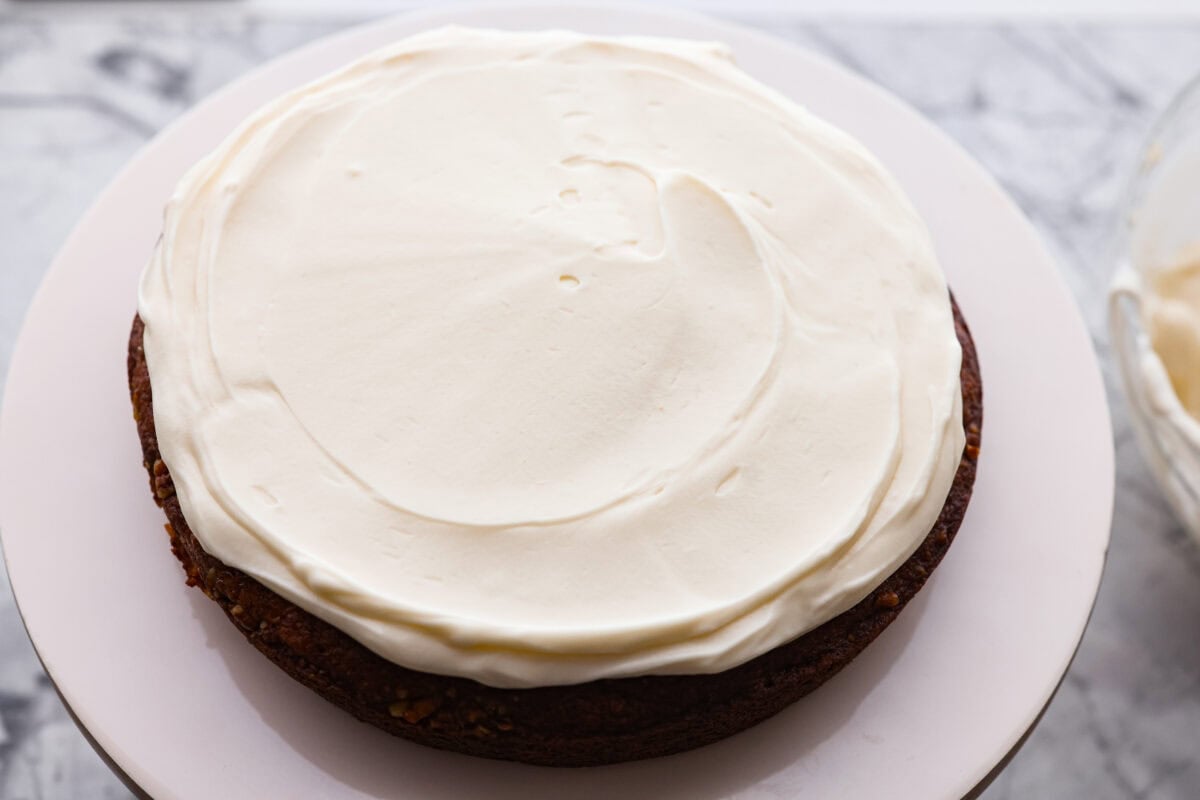If youโve never had hummingbird cake, just know itโs one of those cakes people take a bite of and immediately ask for the recipe. Itโs soft, sweet, packed with banana and pineapple, and topped with a cream cheese frosting that is to die for! First layer of hummingbird cake with a layer of frosting on top.