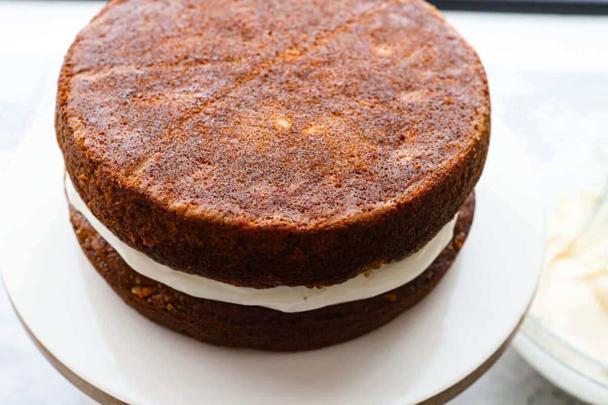 If youโve never had hummingbird cake, just know itโs one of those cakes people take a bite of and immediately ask for the recipe. Itโs soft, sweet, packed with banana and pineapple, and topped with a cream cheese frosting that is to die for! Second layer of cake added to on top of the layer of frosting.