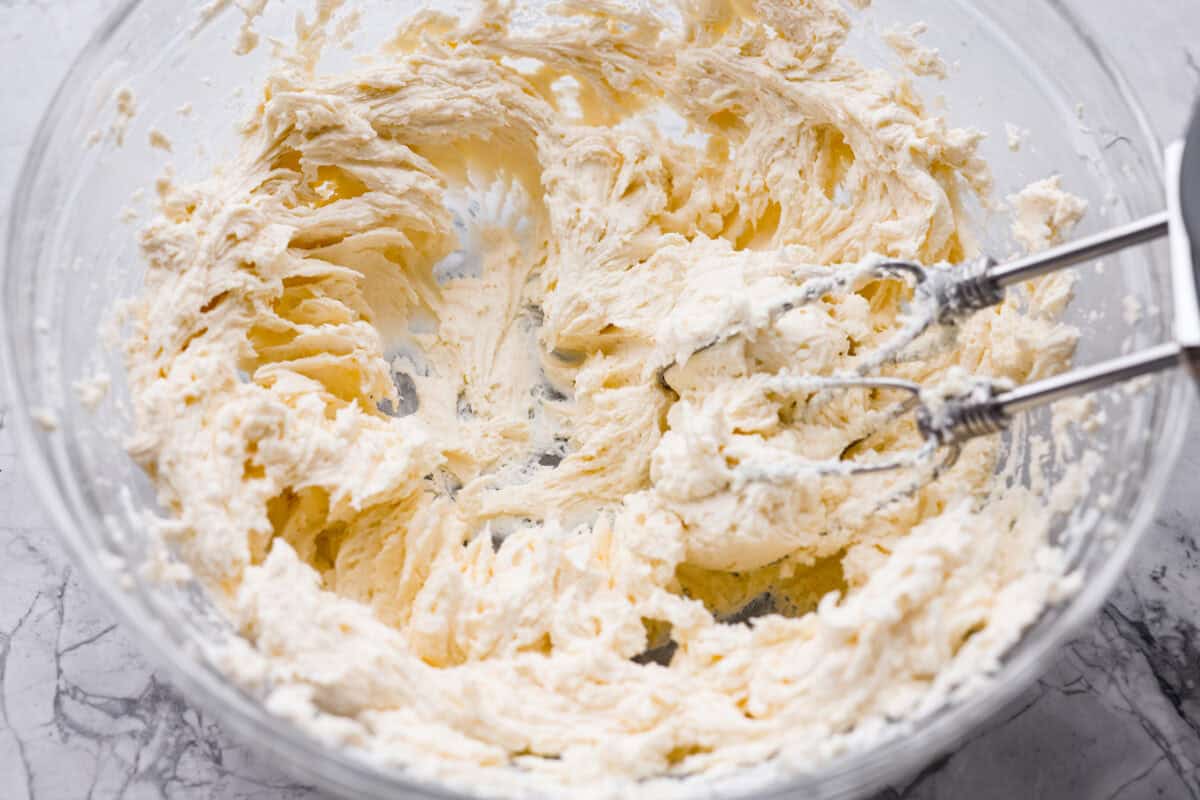 If youโve never had hummingbird cake, just know itโs one of those cakes people take a bite of and immediately ask for the recipe. Itโs soft, sweet, packed with banana and pineapple, and topped with a cream cheese frosting that is to die for! Cream cheese and butter mixed together in a mixing bowl with a hand mixer.
