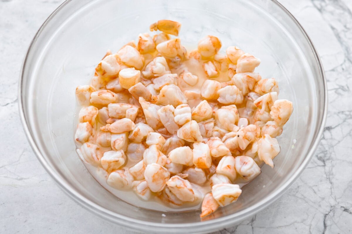 Shrimp being cooked in a bowl of lime juice. 