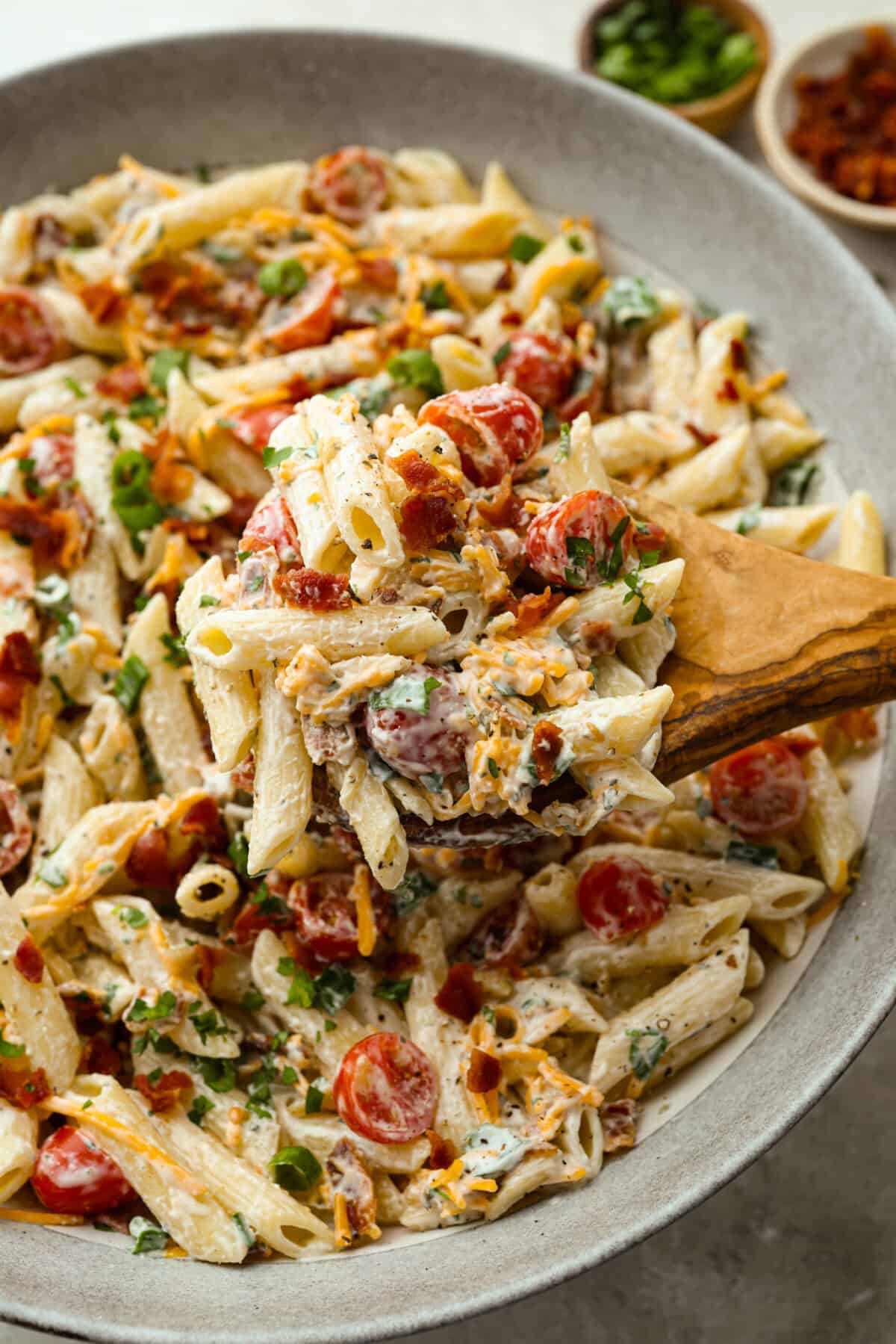 Someone taking a large spoonful of million dollar pasta salad out of the large serving bowl.